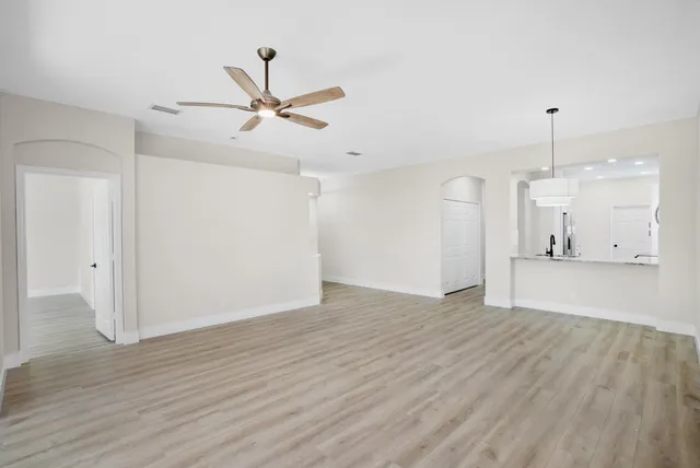 a view of a livingroom with a ceiling fan wooden floor and a ceiling fan