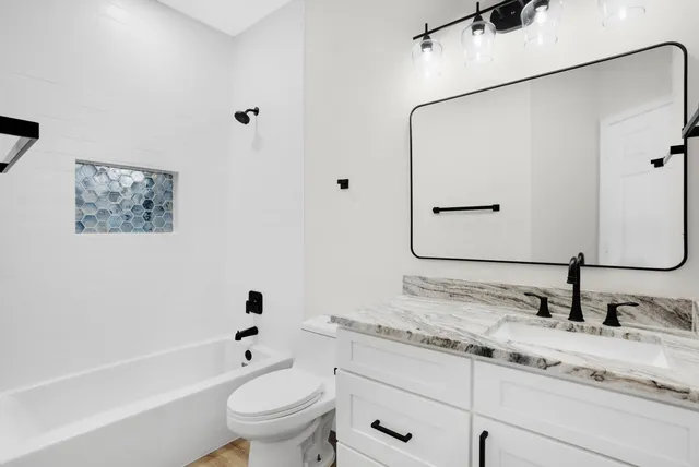a bathroom with a granite countertop sink toilet and shower