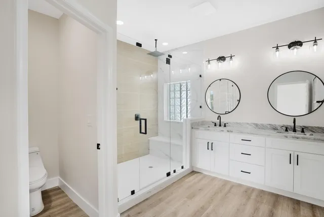 a bathroom with a double vanity sink mirror and shower
