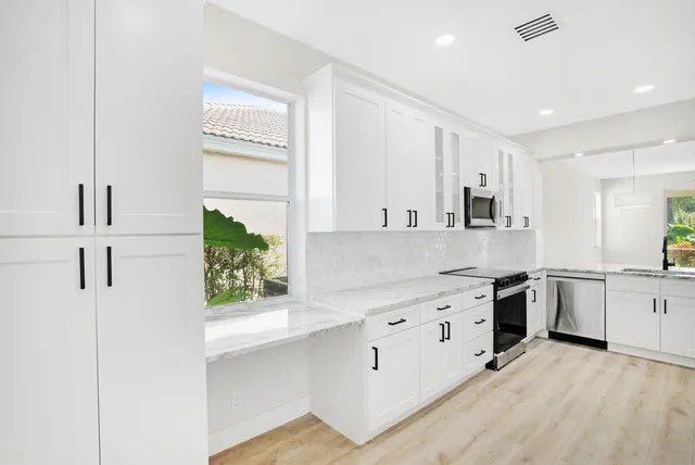 a kitchen with kitchen island white cabinets and white appliances