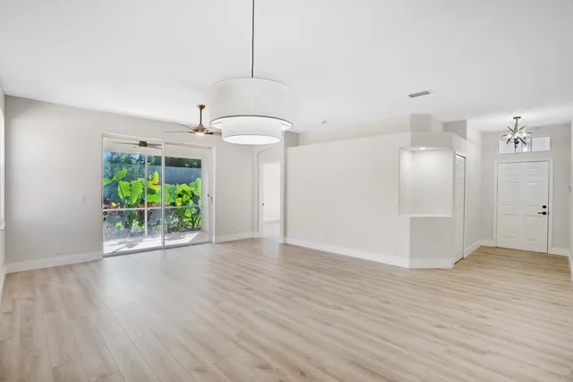 a view of a room with wooden floor potted plants and a ceiling fan