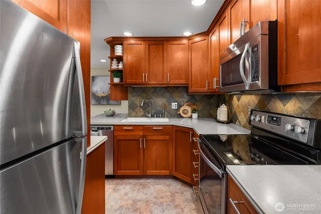 a kitchen with stainless steel appliances granite countertop a refrigerator a stove and a sink
