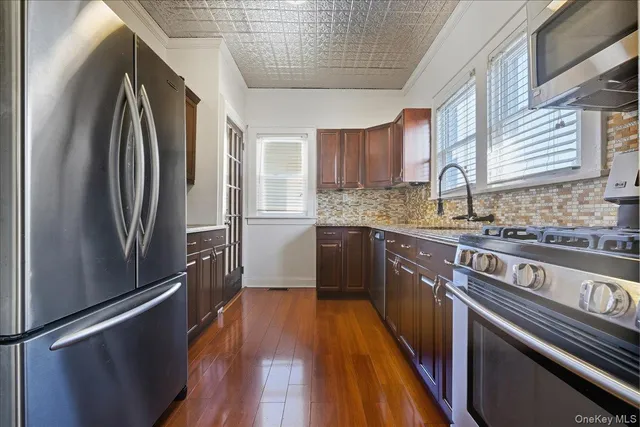 a kitchen with stainless steel appliances granite countertop a refrigerator a sink dishwasher a stove and white countertops with wooden floor