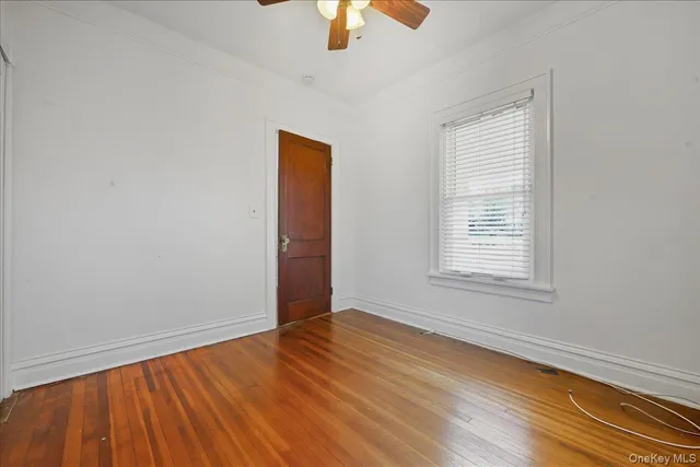 an empty room with a window and a chandelier fan