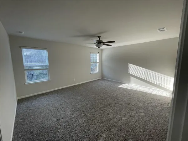 an empty room with windows and fan