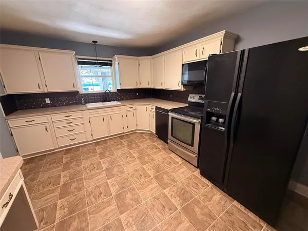 a kitchen with granite countertop a refrigerator stove and sink