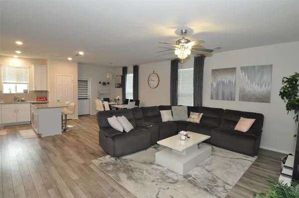 a living room with couches and kitchen view with wooden floor