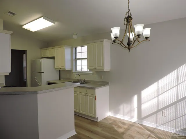 a kitchen with stainless steel appliances granite countertop a sink dishwasher a stove and a chandelier