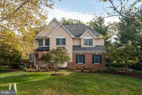 a front view of a house with a garden and trees