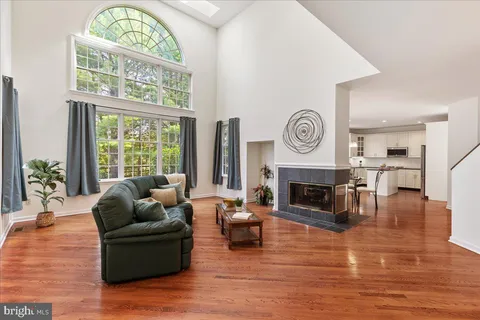 a living room with furniture a fireplace a clock and a large window