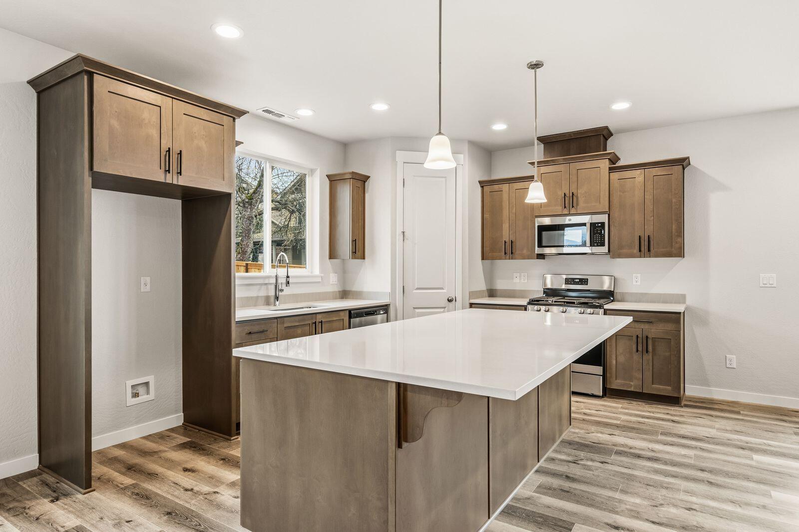 669 Old Waverly Way, Unit 20 Eagle Point, OR 97524 - Photo 9 of 32 a large kitchen with kitchen island a sink stainless steel appliances and cabinets
