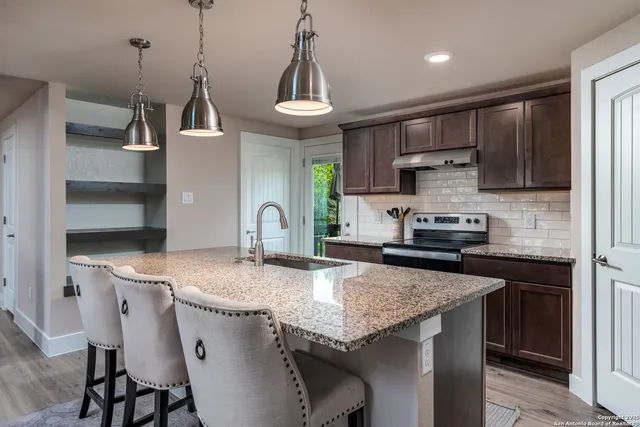 a kitchen with stainless steel appliances granite countertop a sink stove and refrigerator