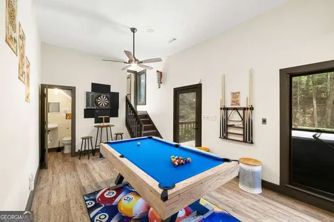 a living room with furniture pool table wooden floor and windows