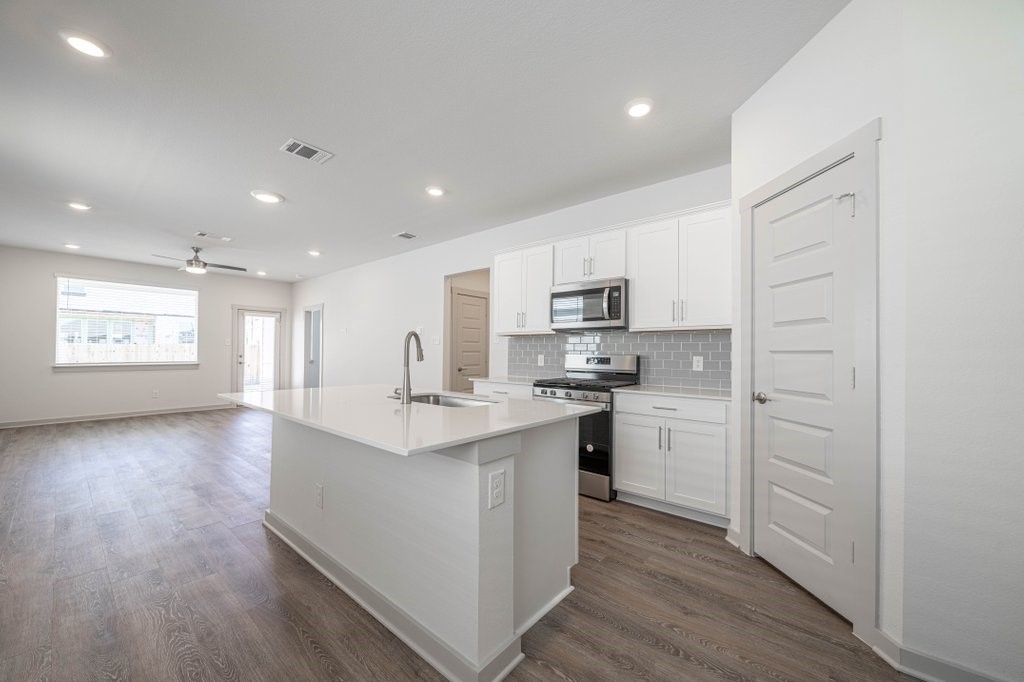 225 New Hampton Way San Marcos, TX 78666 - Photo 7 of 34 a kitchen with stainless steel appliances a sink dishwasher a refrigerator and white cabinets with wooden floor