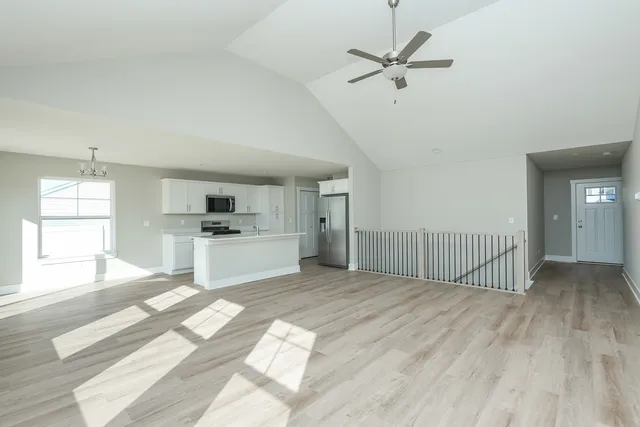 a view of empty room with wooden floor and fan