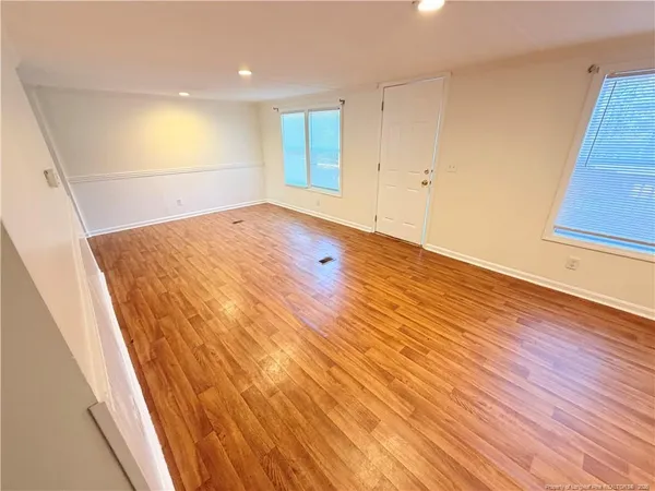 an empty room with wooden floor and windows