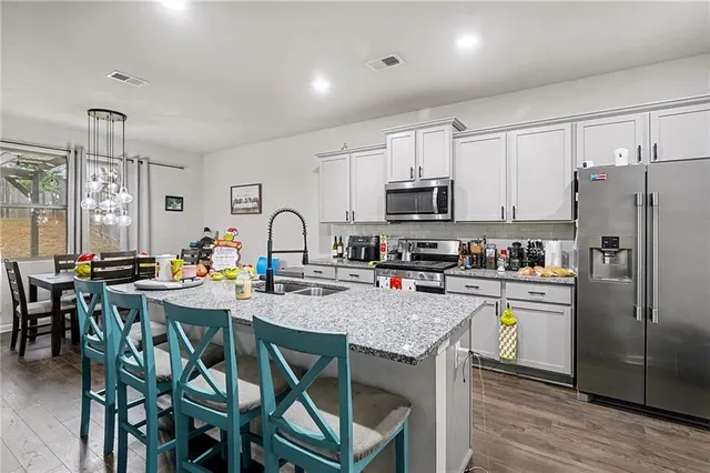 a kitchen with stainless steel appliances granite countertop a table chairs microwave and refrigerator
