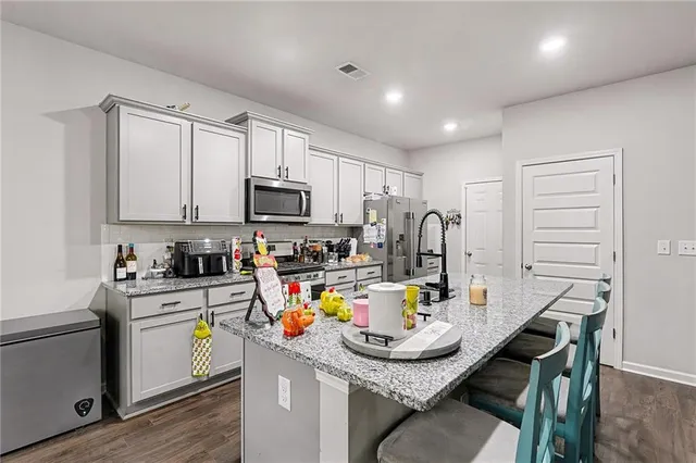 a kitchen with stainless steel appliances granite countertop a sink a stove a microwave a center island and cabinets
