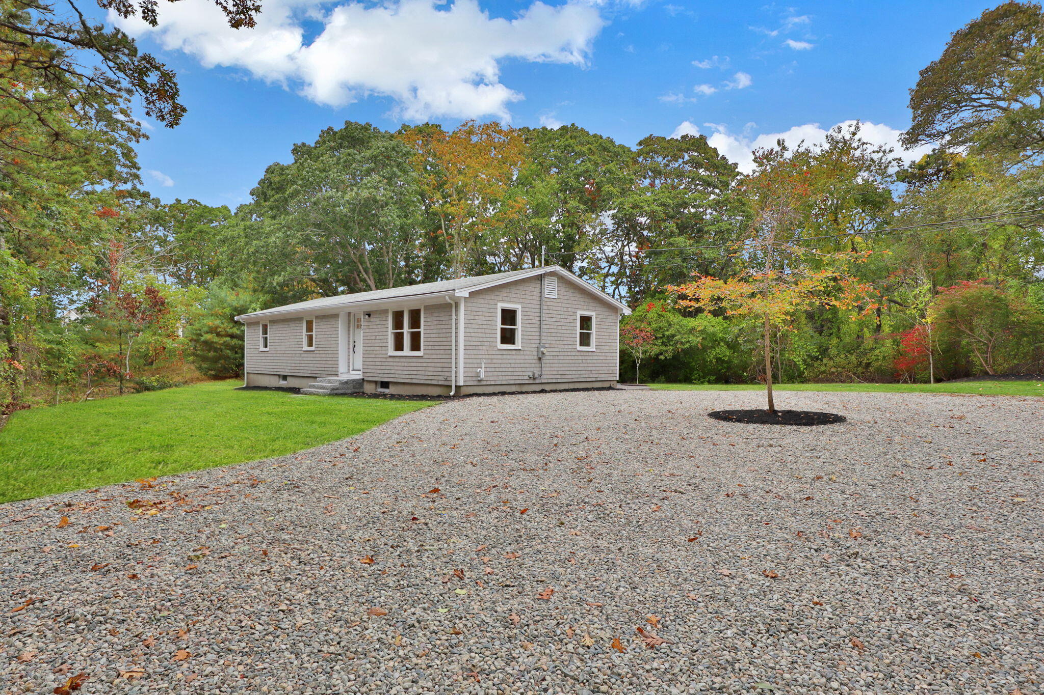 145 Stony Brook Road Brewster, MA 02631 - Photo 3 of 42 a yellow house with a big yard and large trees