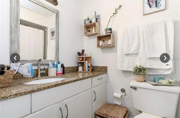 a bathroom with a granite countertop toilet sink and mirror