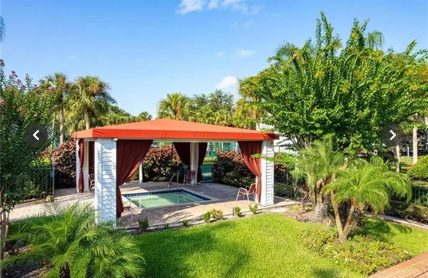 a view of a backyard with table and chairs under an umbrella with plants
