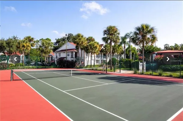 a view of tennis court with palm trees