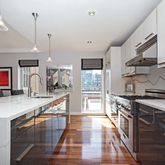 a kitchen with stainless steel appliances granite countertop a sink a stove and a wooden floors