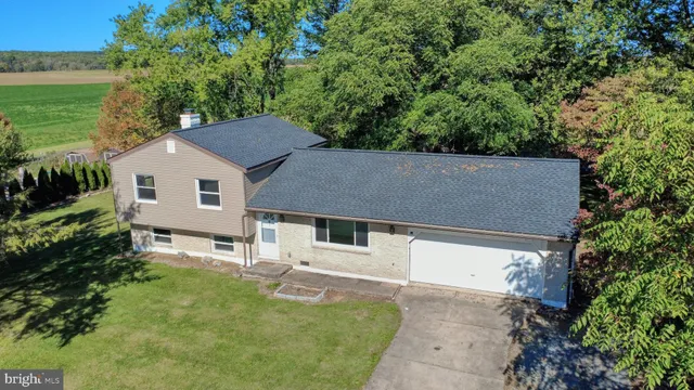 a aerial view of a house next to a big yard and large trees
