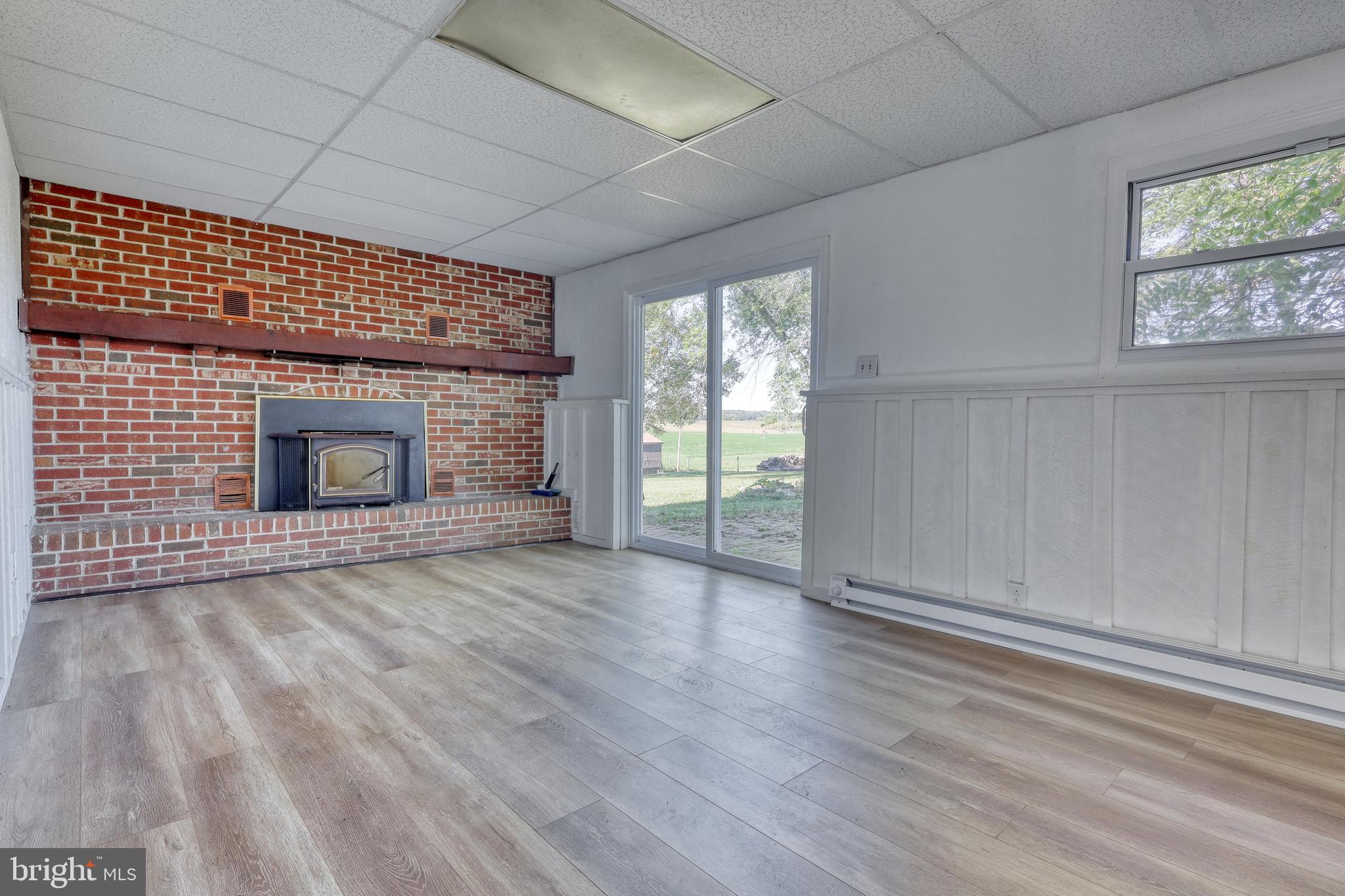 125 Ramblewood Road Pennsylvania Furnace, PA 16865 - Photo 21 of 36 an empty room with wooden floor fireplace and windows