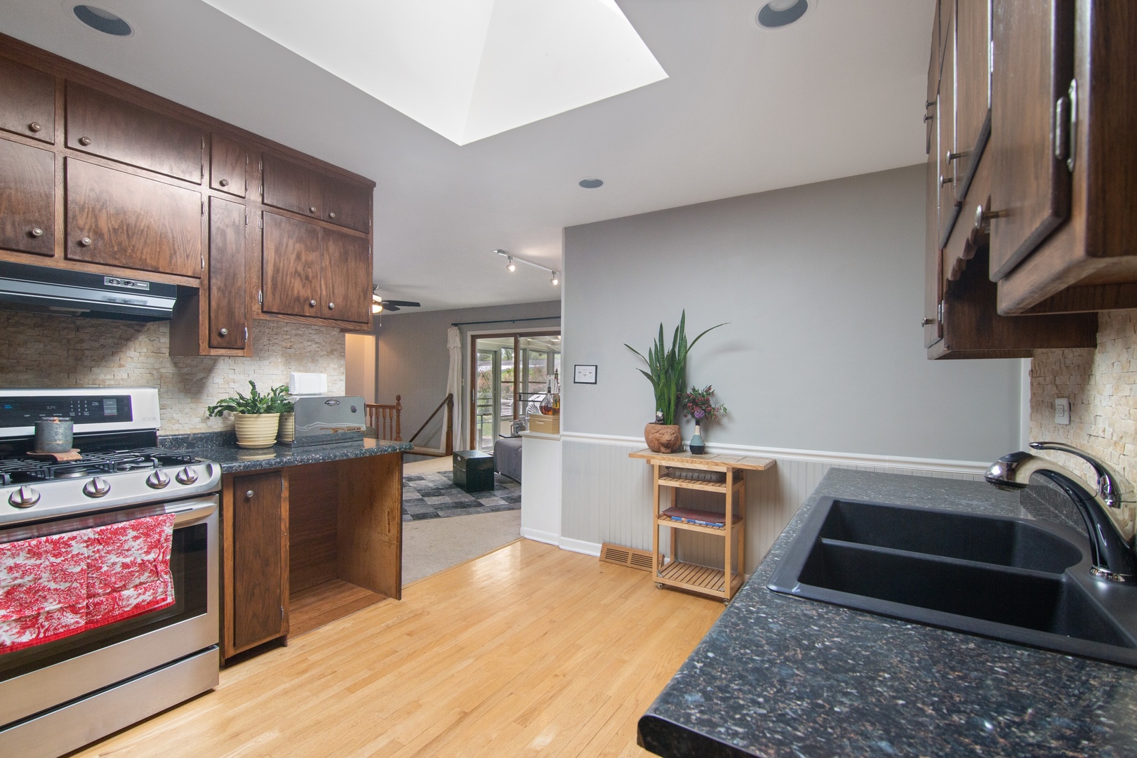936 Pebble Drive Wheeling, IL 60090 - Photo 5 of 27 a kitchen with stainless steel appliances granite countertop a stove a sink dishwasher a microwave oven and a dining table with wooden floor