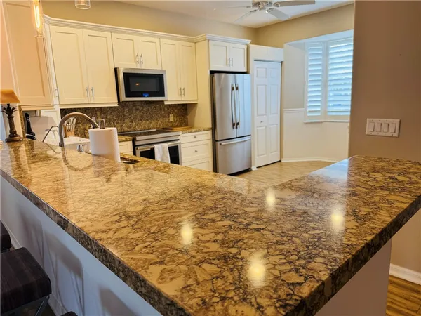 a kitchen with kitchen island granite countertop a sink appliances and cabinets