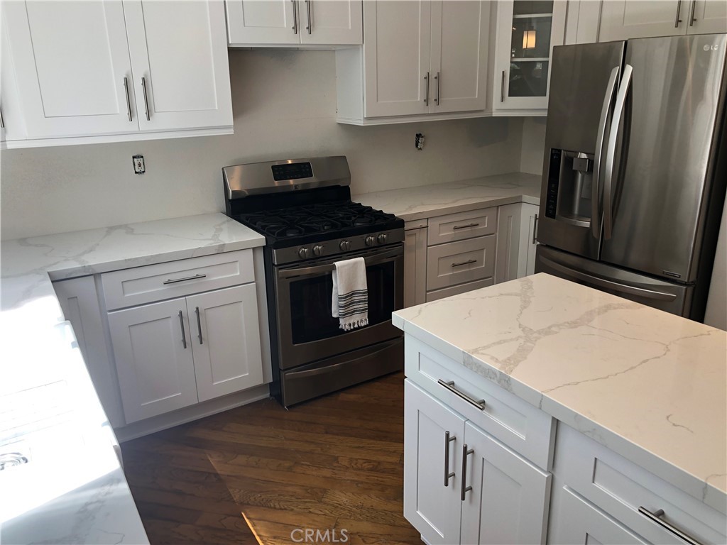 3095 Promenade Costa Mesa, CA 92626 - Photo 5 of 10 a kitchen with white cabinets and stainless steel appliances