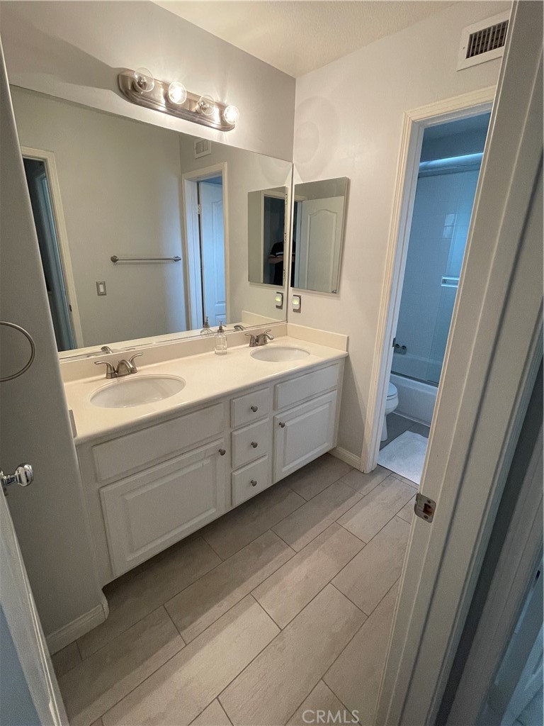 3095 Promenade Costa Mesa, CA 92626 - Photo 8 of 10 a bathroom with a double vanity sink a mirror and a bathtub