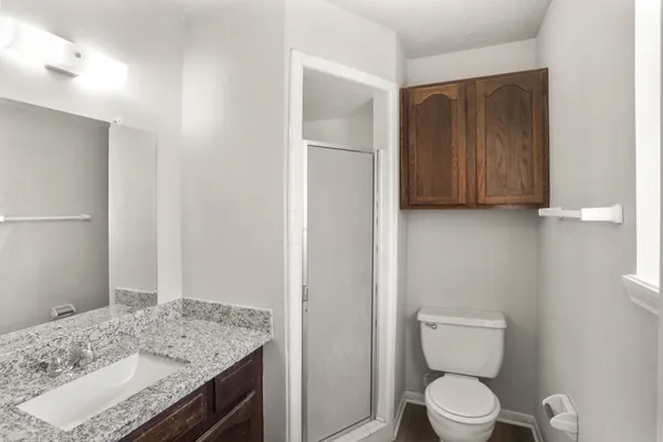 a bathroom with a granite countertop toilet and a sink