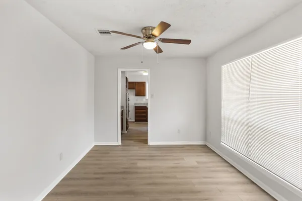 a view of empty room with wooden floor and fan