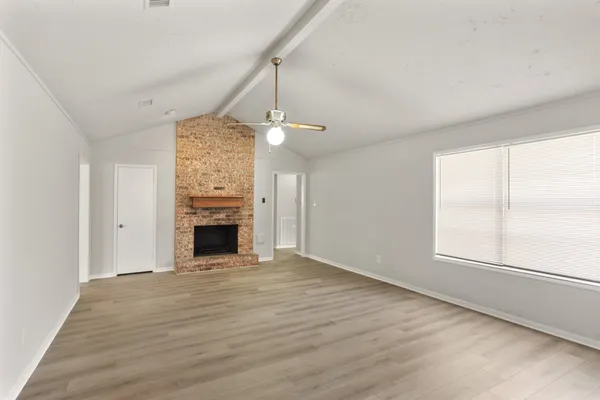 an empty room with windows and fireplace