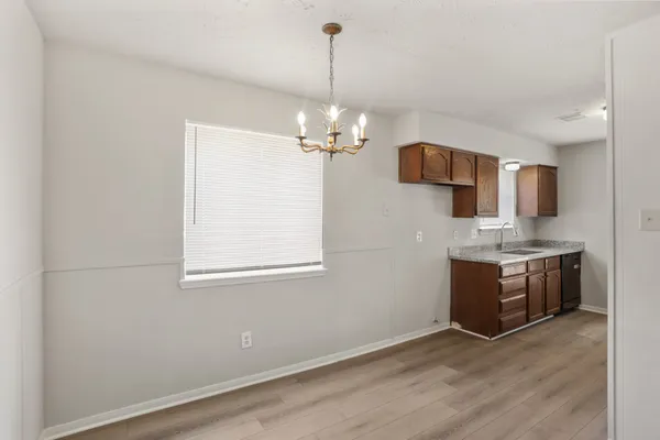 a view of a kitchen with granite countertop a sink and dishwasher a oven with wooden floor