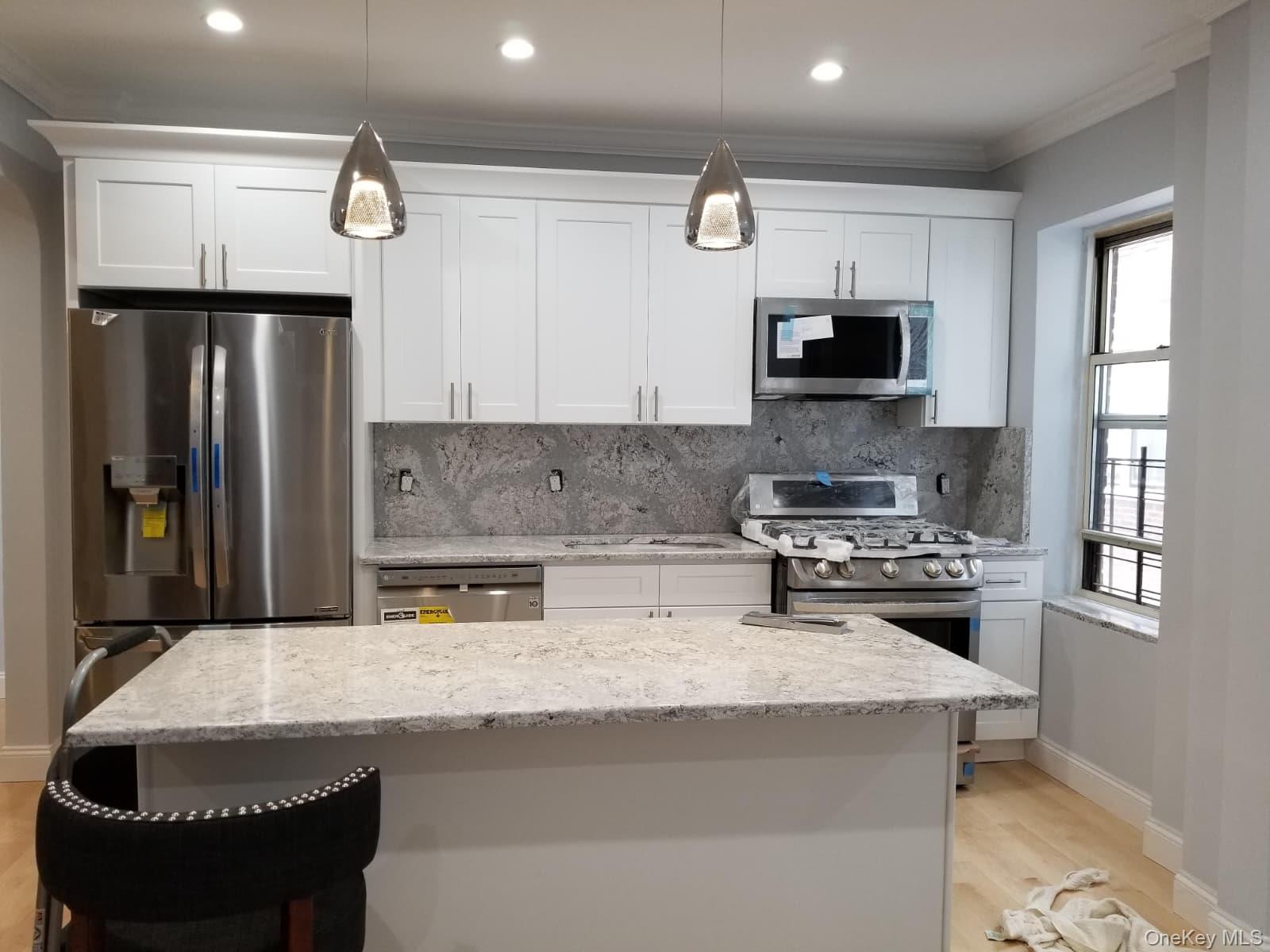 a kitchen with kitchen island granite countertop a stove a sink a refrigerator and a microwave