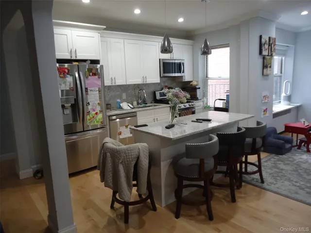 a kitchen with stainless steel appliances kitchen island granite countertop a table chairs and a refrigerator