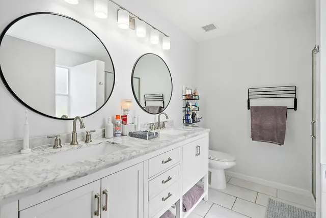 a bathroom with a granite countertop double vanity sink and a mirror