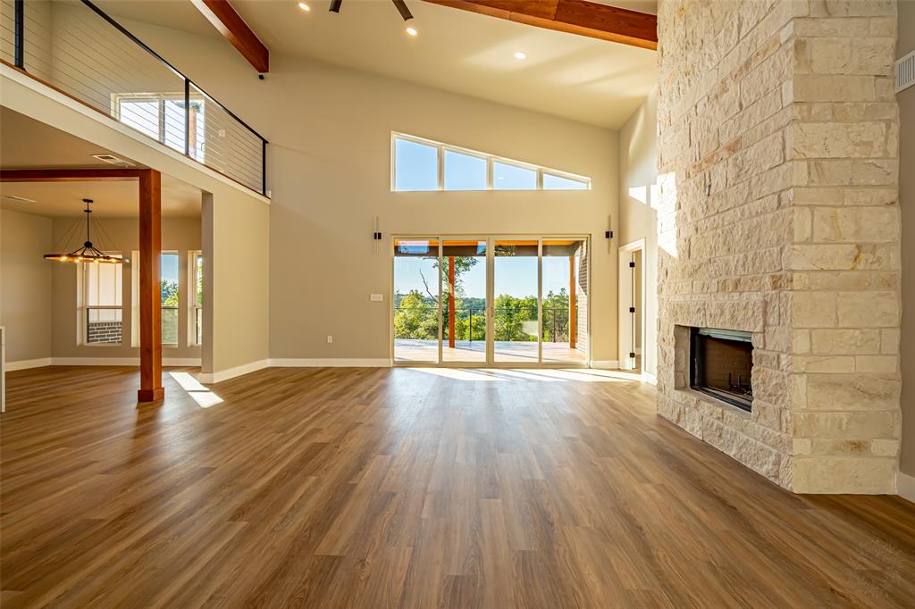 2128 Eagles Rdg Drive Weatherford, TX 76087 - Photo 23 of 39 Unfurnished living room with beamed ceiling, a stone fireplace, wood finished floors, a towering ceiling, and recessed lighting