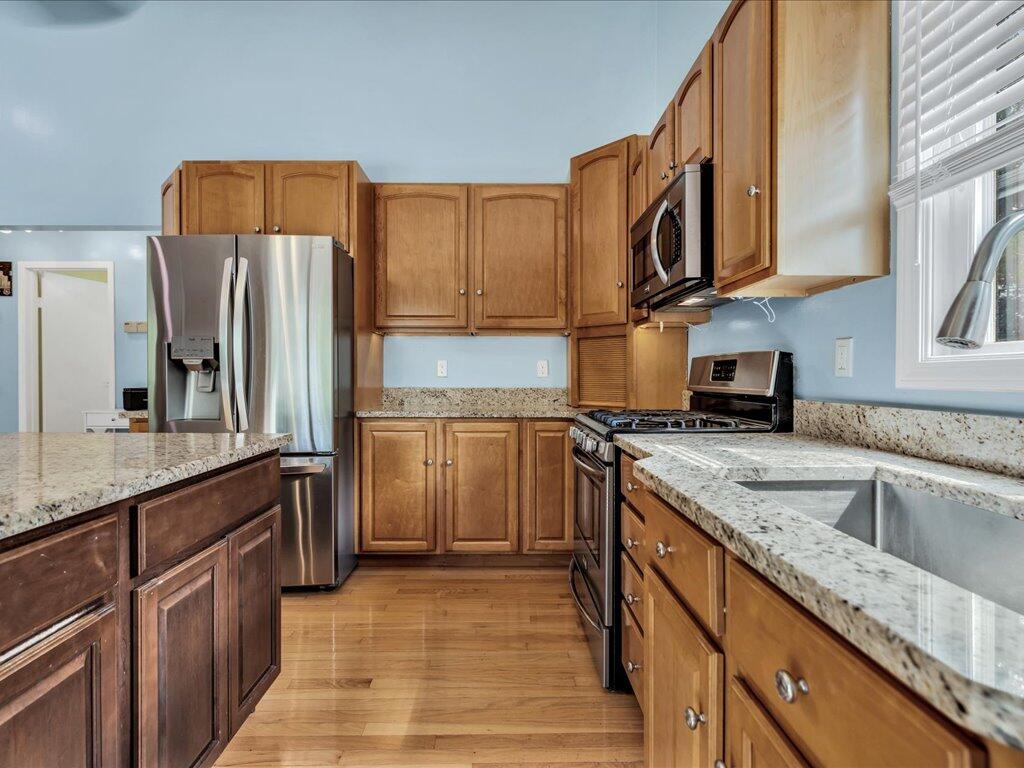 62 Deer Ridge Road Mashpee, MA 02649 - Photo 15 of 40 a kitchen with stainless steel appliances granite countertop a refrigerator a stove and a sink with wooden cabinets