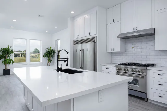 a kitchen with granite countertop a sink a stove and cabinets
