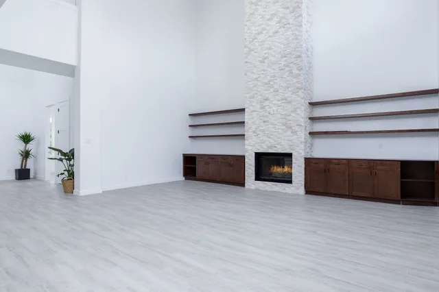 a view of empty room with wooden floor and fireplace