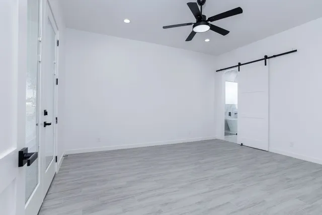 an empty room with wooden floor and a ceiling fan
