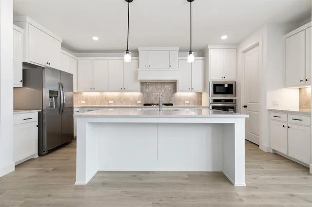 a kitchen with kitchen island white cabinets and stainless steel appliances