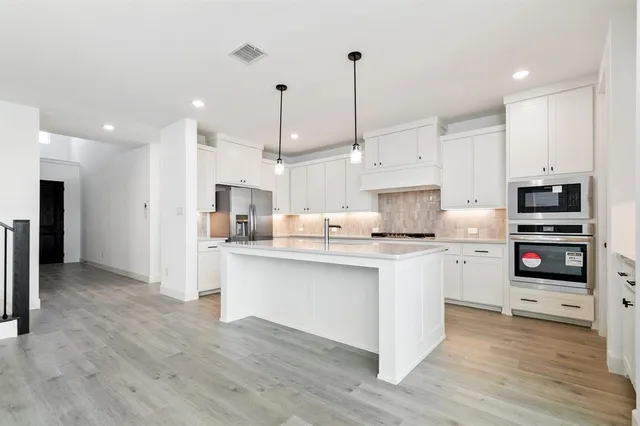 a kitchen with stainless steel appliances kitchen island a stove a refrigerator a sink and a oven