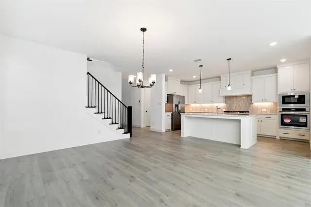 a view of a kitchen with stainless steel appliances granite countertop a stove a refrigerator a sink dishwasher with wooden floor and cabinets