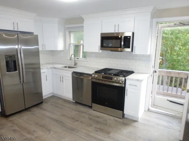 a kitchen with stainless steel appliances granite countertop a stove a sink and a refrigerator