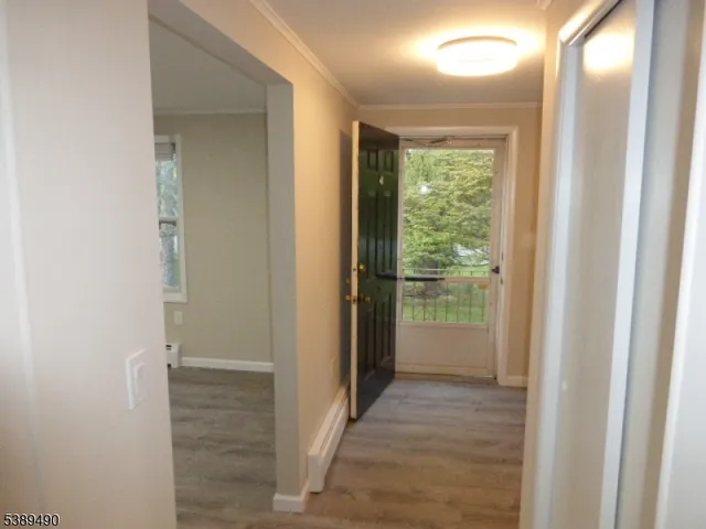 a view of a hallway with wooden floor and a bathroom